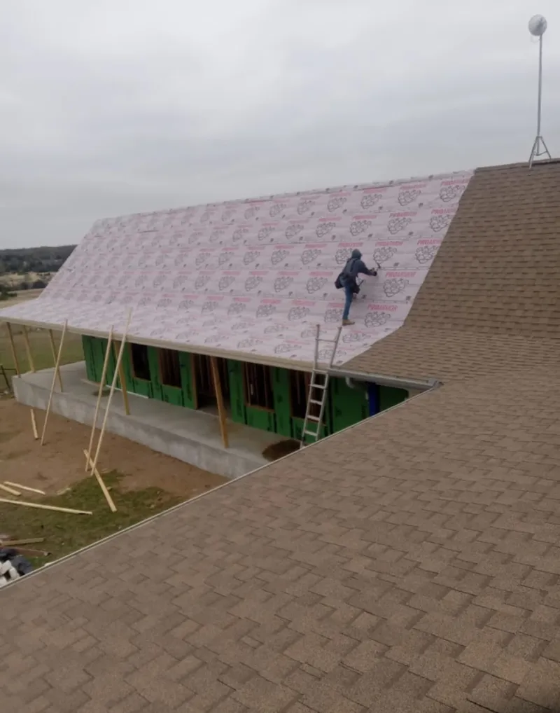 Worker preparing underlayment for a metal roof installation in Guadalupe